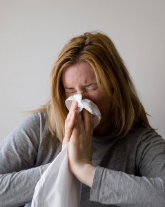 sick Woman blowing her nose on tissue. 