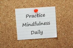 Paper on wooden board with words "practice mindfulness daily"