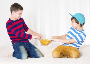 Two kids misbehaving fighting over chips