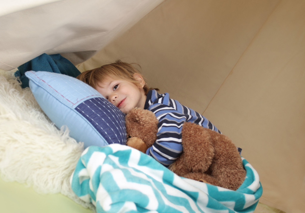 young boy With Sleep Disorder laying down with teddy bear wide awake.