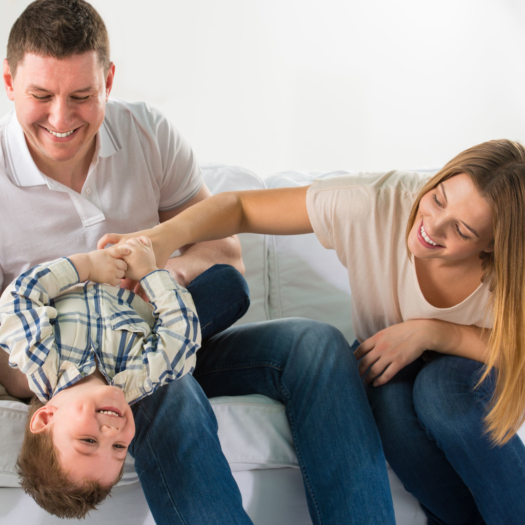 Mother and Father laughing and playing around with their son.