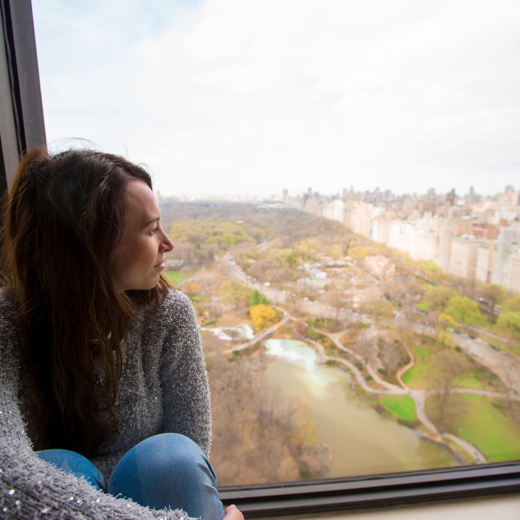 Woman looking outside window, the view of Central park