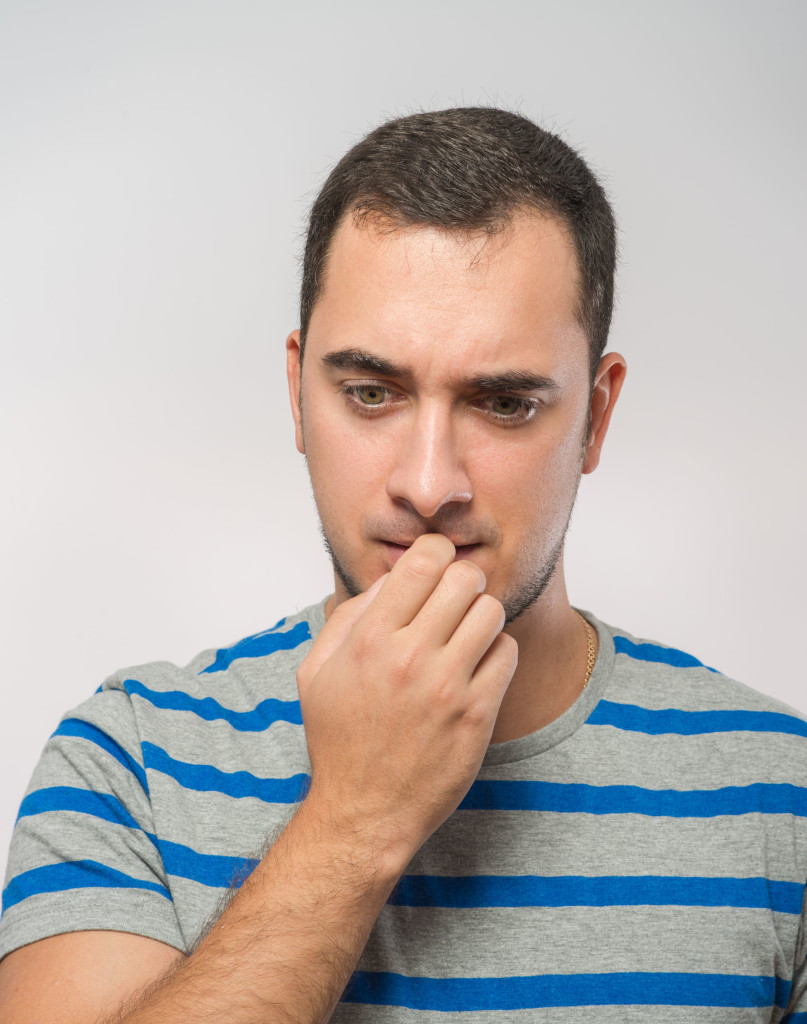 Stressed man with bad habit of biting his nails.