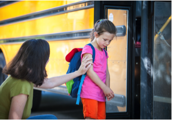child with Chronic pain not wanting to get into school bus. Mother is bent down consulting child.