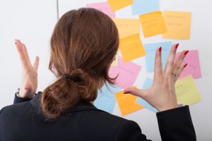 Women stressed looking at post-its on board. 