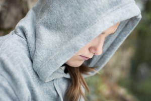 depressed teen girl with her head down and hoodie on. 