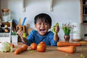 Child throwing tantrum squeezing vegetables 