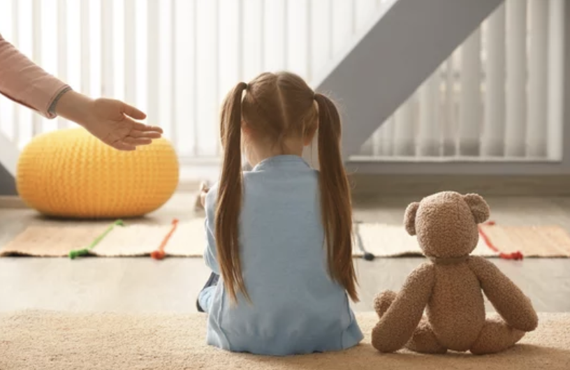 Depressed Little girl sitting on floor with teddy bear.