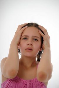 Anxious young girl holding her head.