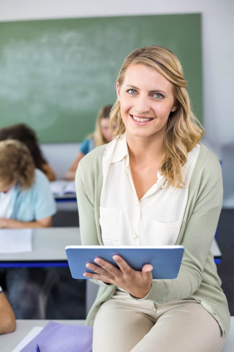 Psychologist woman sitting on table with tablet smiling. 