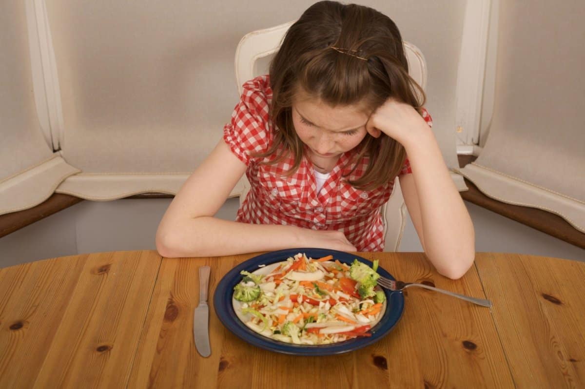 Picky eater Child sitting at table not touching food. 