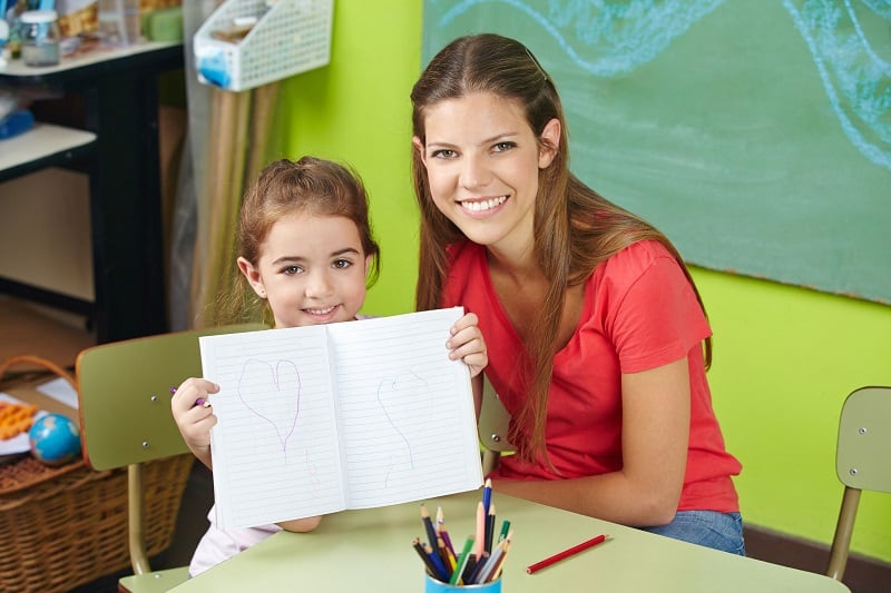 Psychologist smiling with child in a school.
