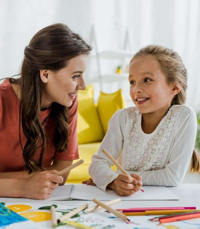 ABA Therapist helping and talking to child while doing activity