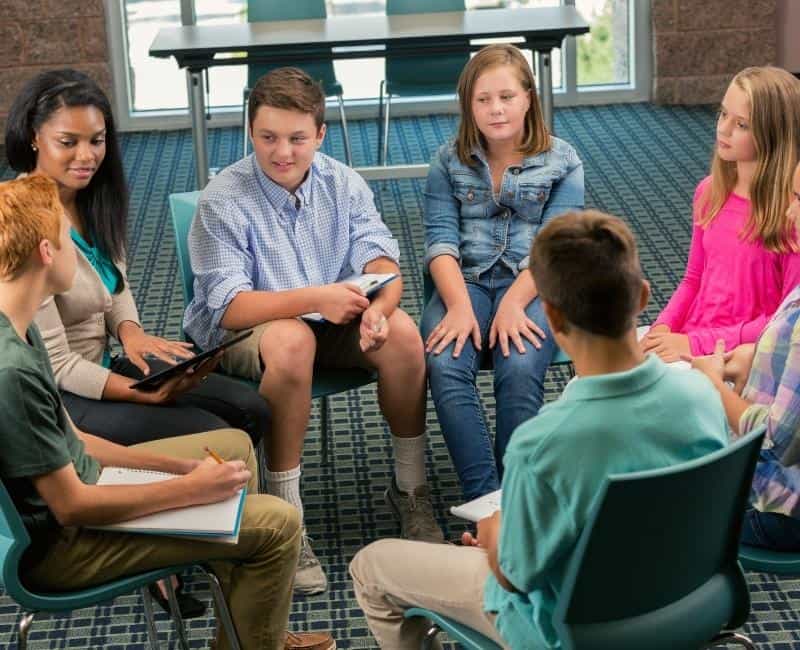 Group of tweens in circle discussing.