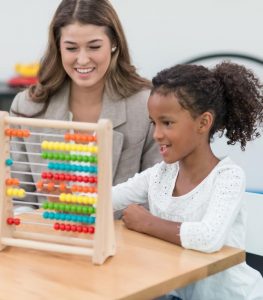 ABA Therapist helping child with group session activity.