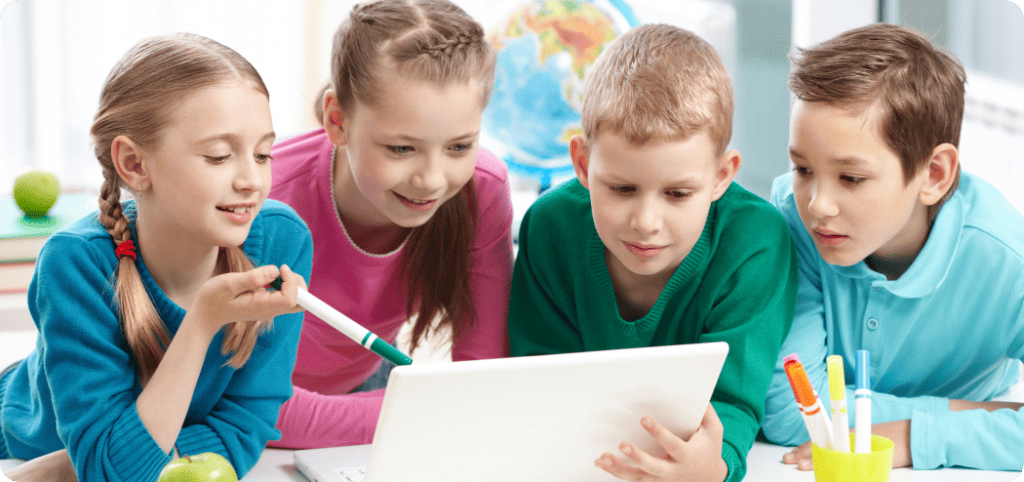 four kids in school looking at paper assignment.