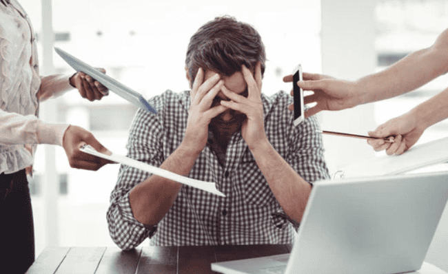 Man stressed at work but people handing him more stressful work.