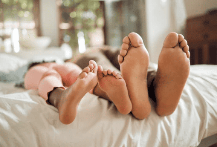 feet of mother and child sleeping on bed.