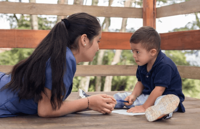 psychologist helping little boy with Autism do writing activity.
