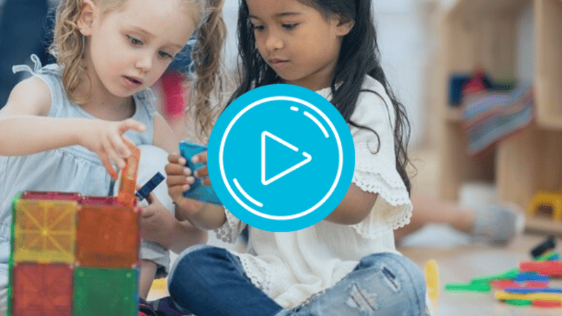 Two young girls playing with shapes in classroom
