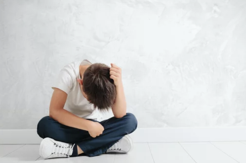 depressed child sitting on floor in empty room.