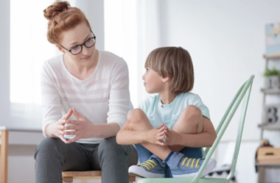 Psychologist talking to Anxious child, both sitting down.