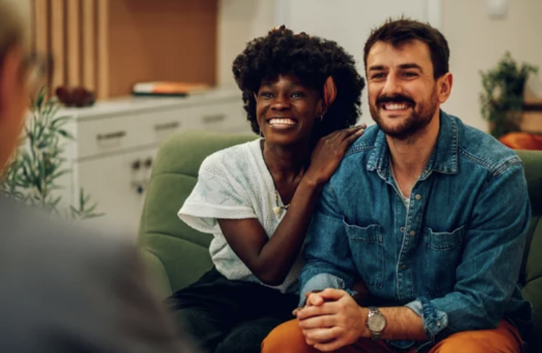 Couple in Therapy session on couch smiling.