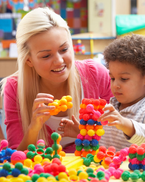 PCIT Therapist smiling while helping toddler with shape activity.