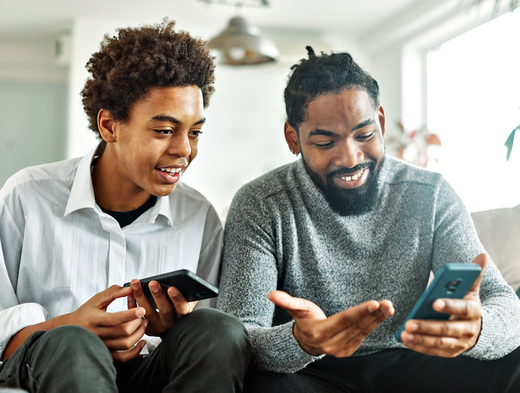 Father and son holding their phones and laughing