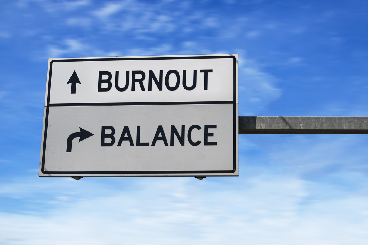 Burnout versus balance. White two street signs with arrow on metal pole. Directional road. Crossroads Road Sign, Two Arrow. Blue sky background.